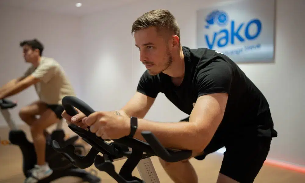hombre pedaleando rápido y agachado durante una clase de spinning