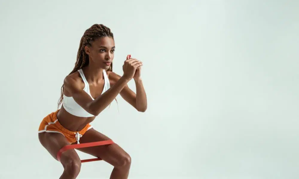 mujer haciendo squat isométrica con cinta elástica