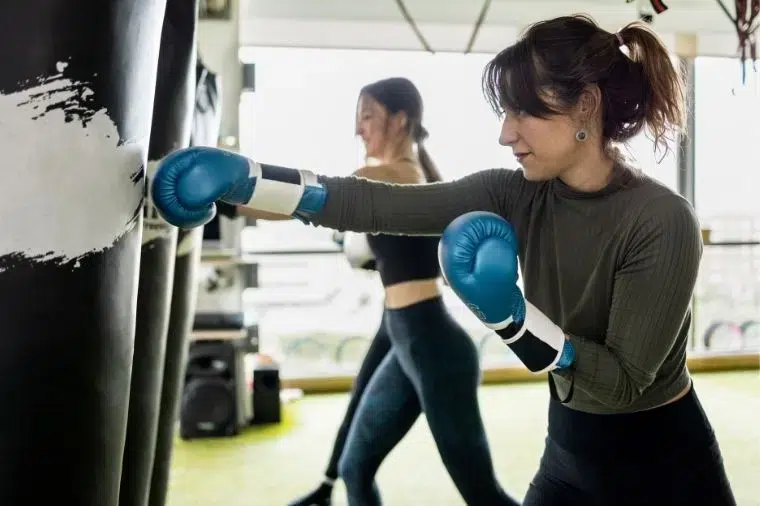 mujeres golpeando saco de boxeo en clase de boxing