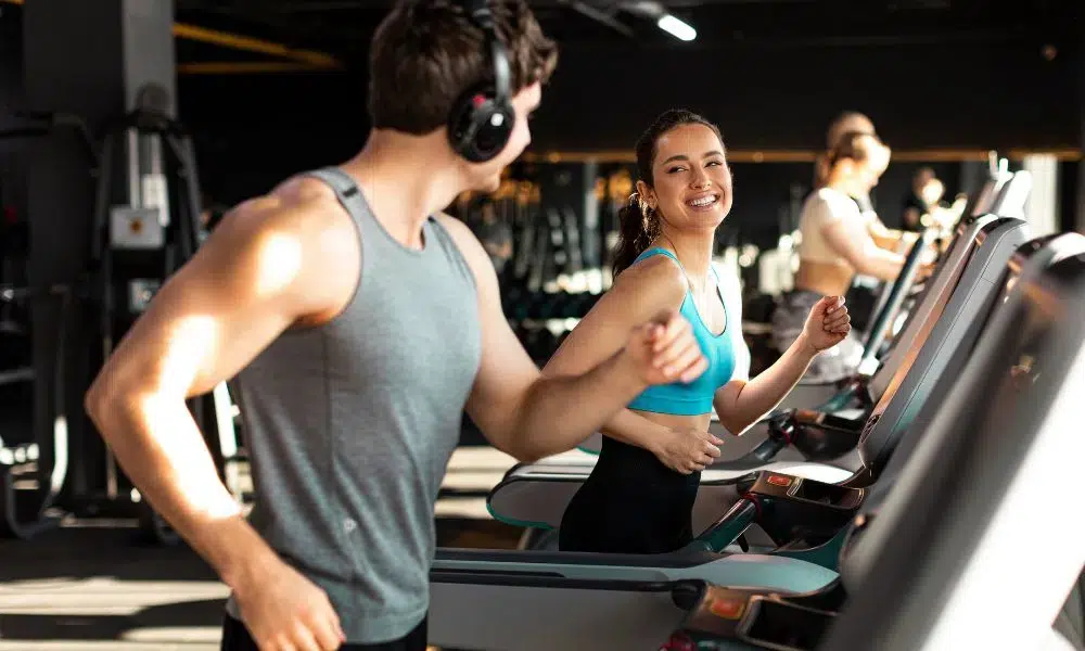 pareja calentando en cinta de correr gimnasio