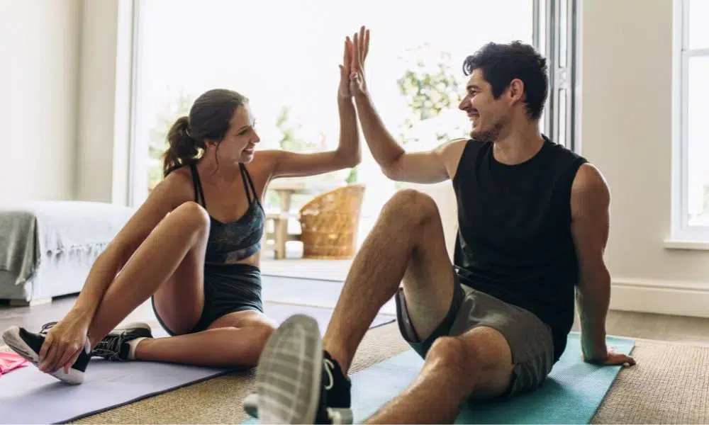 pareja chocando la mano despues de sesion de deporte en casa