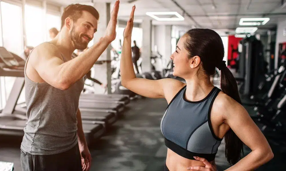 chico y chica chocando la mano en el gym