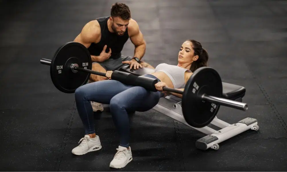 coach ayudando a socia a hacer hip thrust