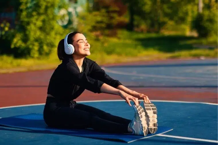chica estirando en pista de basket mientras escucha musica en sus cascos