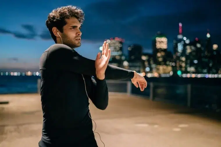 chico estirandose en la puesta de sol en afueras de ciudad