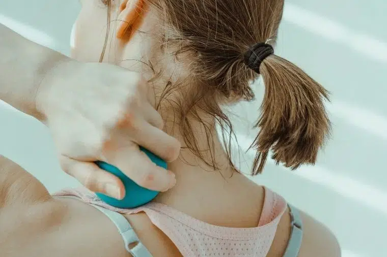 mujer masajeandose con pelota de masaje
