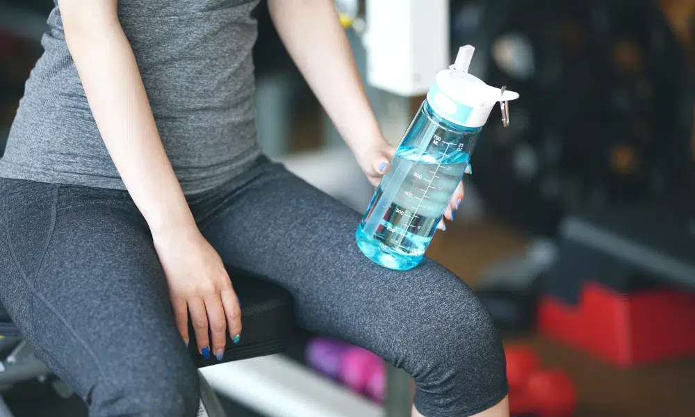 mujer utilizando una cantimplora para ir al gimnasio