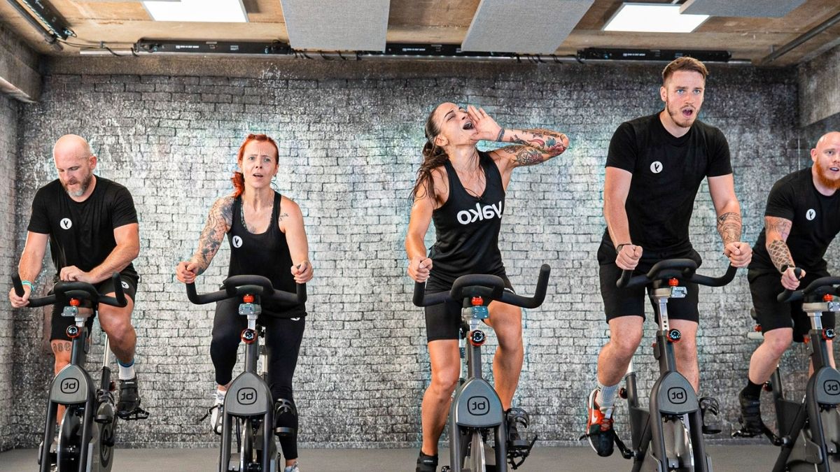 coachs alentando a socios encima de bicicletas indoor