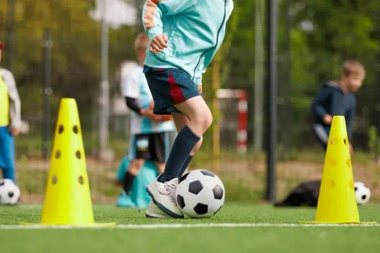 joven esquivando conos en entrenamiento de fútbol